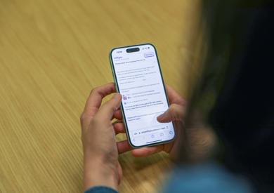 A person holding a smartphone with a text message conversation on the screen.