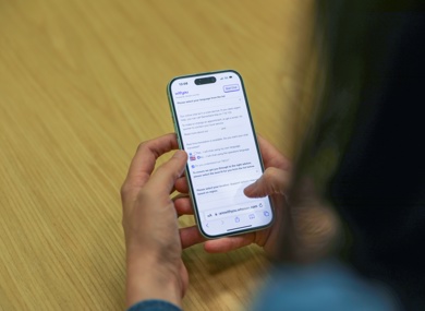 A person holding a smartphone with a text message conversation on the screen.